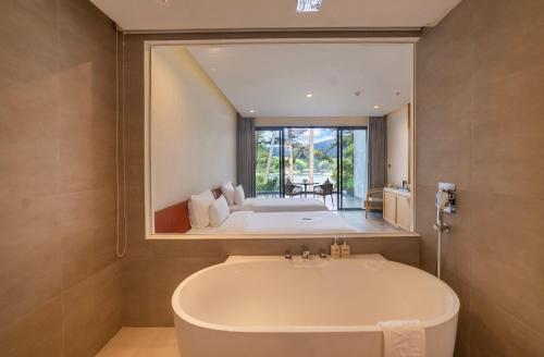 a bathroom with a tub and a large mirror at Haven in the Pines in Da Lat