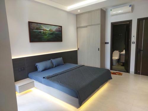 a bedroom with a blue bed and a bathroom at Maison Art in Quy Nhon