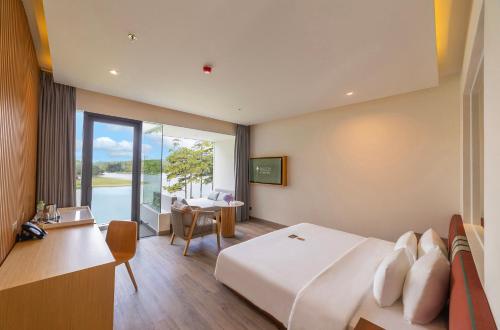 a hotel room with a bed and a desk and a window at Haven in the Pines in Da Lat