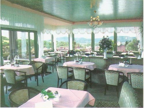ein Esszimmer mit Tischen, Stühlen und Fenstern in der Unterkunft Gästehaus Café Ruff in Happurg