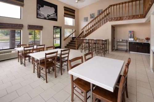 a dining room with tables and chairs and a staircase at Super 8 by Wyndham Longmont/Twin Peaks in Longmont