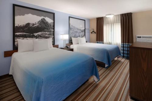 a hotel room with two beds and a television at Super 8 by Wyndham Longmont/Twin Peaks in Longmont