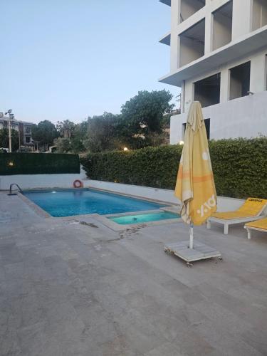 an umbrella and chairs next to a swimming pool at Cicek Apart Hotel in Çeşme