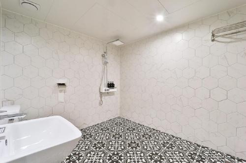 a white bathroom with a tub and a sink at Jamsil Tomgi Hotel in Seoul