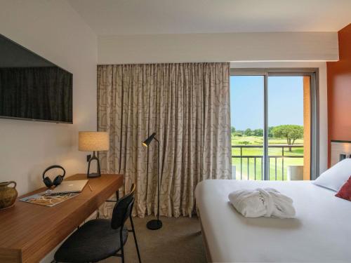 a hotel room with a bed and a desk and a window at Mercure Toulouse Aéroport Golf de Seilh in Seilh