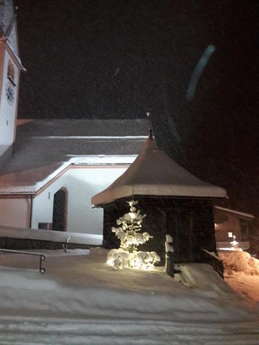 a building with a gazebo in the snow at night at Appartement Alpina in Alpbach
