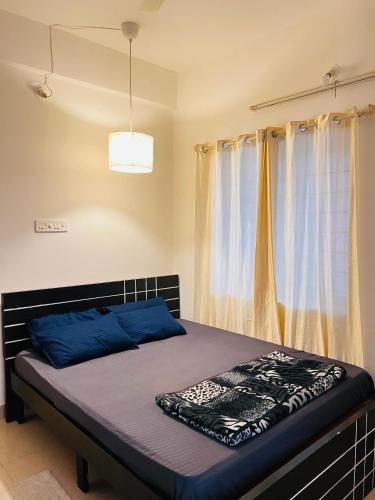 a bedroom with a bed with blue sheets and a window at Electrifying Pearl in Bangalore