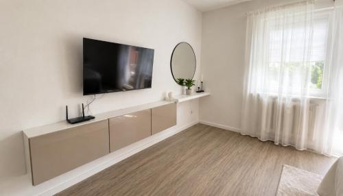 a white living room with a flat screen tv on a wall at Ferienwohnung an der Steinmauer in Bad Kissingen