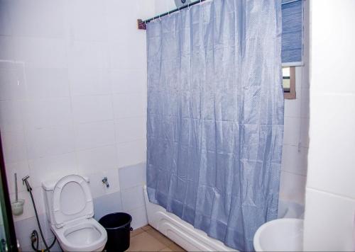 a bathroom with a toilet and a shower curtain at Seven Hills Suites in Makurdu