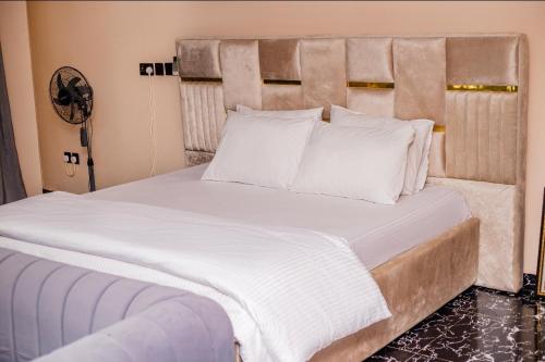 a bedroom with a large bed with white sheets and pillows at Seven Hills Suites in Makurdu