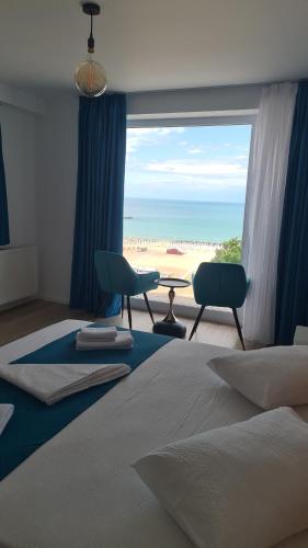a bedroom with a bed and a view of the beach at Ella Apart Hotel in Constanţa
