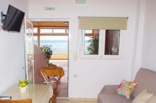 a living room with a couch and a table and a window at Sunny Apartments in Makry Gialos