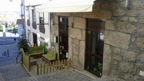 ein Gebäude mit einer Veranda mit einer grünen Bank und einem Tisch in der Unterkunft Abrigo da Estrela in Covilhã