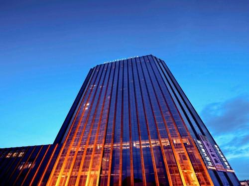 ein hohes Gebäude mit orangefarbenen Glasfenstern in der Abenddämmerung in der Unterkunft Pullman Guiyang in Guiyang