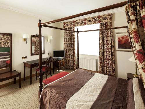 a hotel room with a bed and a desk at Mercure York Fairfield Manor Hotel in York