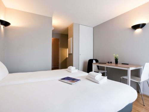a hotel room with two beds and a desk at Aparthotel Adagio Access Paris Maisons-Alfort in Maisons-Alfort
