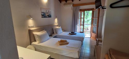 a hotel room with two beds and a window at Villa Kavourakia in Kolios