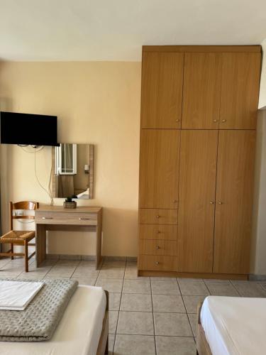 a bedroom with two beds and a desk and a television at Stella Studios in Ilia