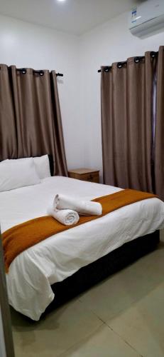 ein Bett mit einer braun-weißen Decke und Vorhängen in der Unterkunft Sunset Villas in Korotogo