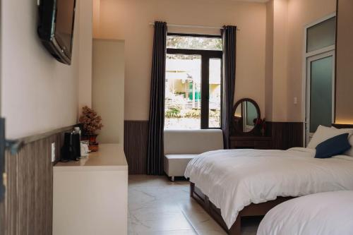 a hotel room with two beds and a window at Gia An Hotel Dalat in Da Lat