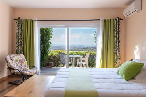 a bedroom with a bed and a balcony with a table at Somptua Garden Boutique Hôtel in Ivato