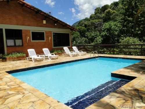 una piscina con sillas y una casa en Pousada Romântica Serra da Mata, en Penedo