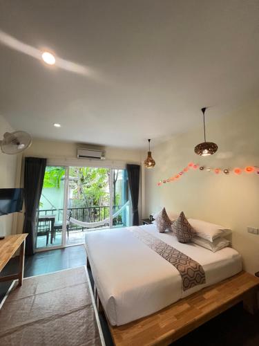 a bedroom with a large bed and a balcony at Benjamin's Hut in Srithanu