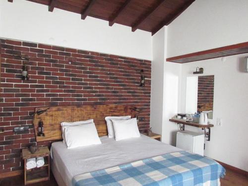 a bed in a room with a brick wall at Amazon Petite Palace in Selçuk