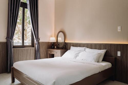 a bedroom with a bed with a mirror and a window at Gia An Hotel Dalat in Da Lat