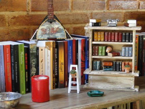 a book shelf filled with books on top of a table at Pousada Romântica Serra da Mata in Penedo