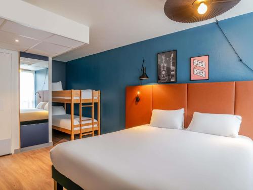 a bedroom with a large bed and a blue wall at ibis Bordeaux Saint Emilion in Saint-Émilion
