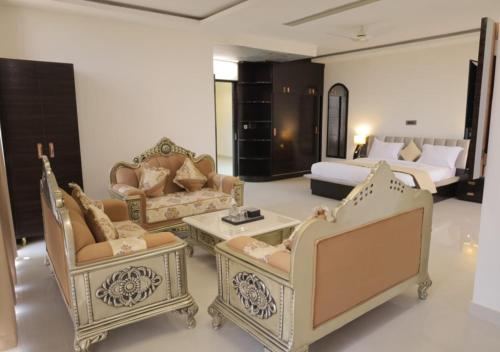 a living room with chairs and a couch and a bed at Hotel Capital in Noida