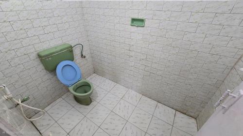 a bathroom with a green toilet with a blue seat at K Cottage in Varkala