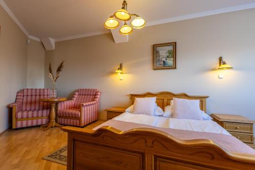 a bedroom with a bed and two chairs at Oportó Panzió in Villány