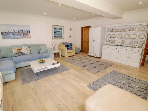a living room with a blue couch and a table at Charlecote House in Saundersfoot