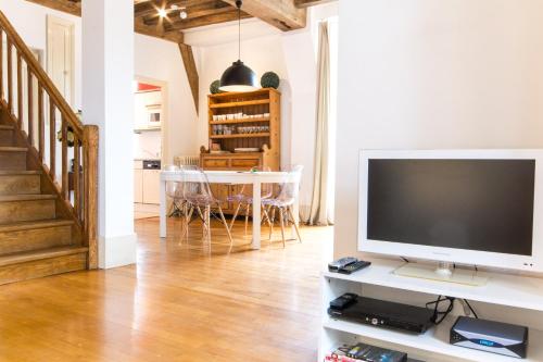a living room with a television and a dining room at Les Bons Enfants in Dijon