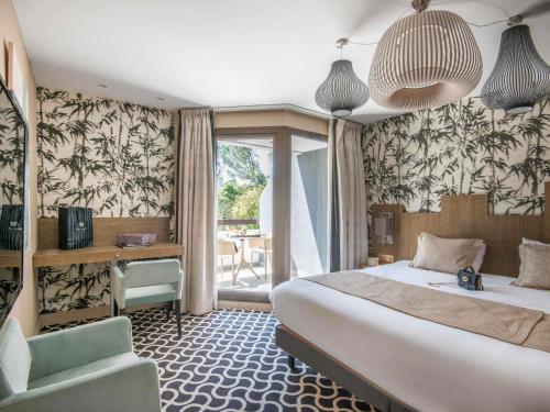 a bedroom with a bed and a desk and a chair at Mercure Brignoles Golf de Barbaroux & Spa in Brignoles