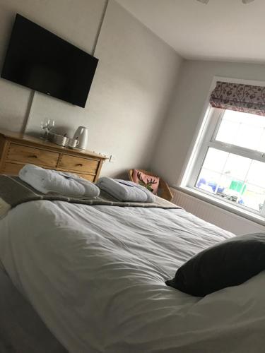 a bedroom with a bed with pillows and a window at Sunrise Guest House in Bude