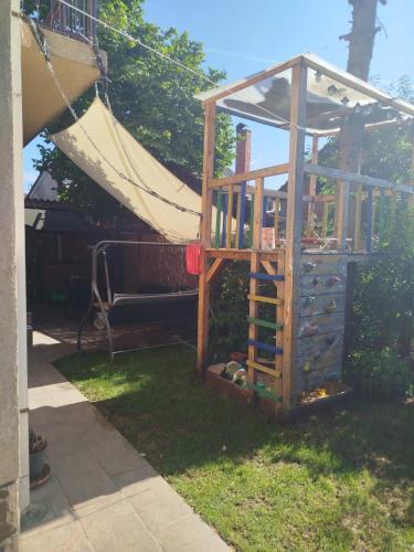 a wooden play house in the yard with a hammock at Fina Apartman in Leskovac