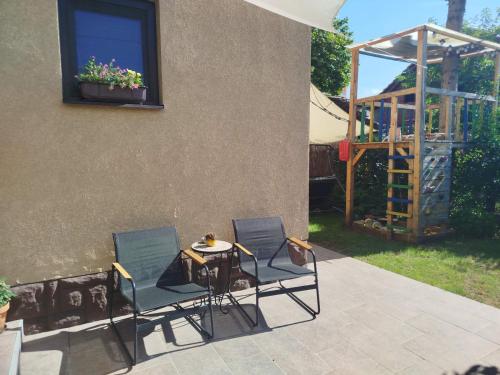 a patio with two chairs and a table and a building at Fina Apartman in Leskovac