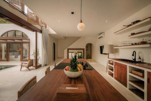 a kitchen and dining room with a wooden table at Suasana by AYA in Uluwatu