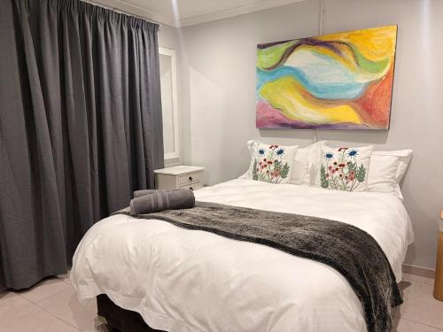 a bedroom with a bed with a painting on the wall at Local Roots in Pinetown