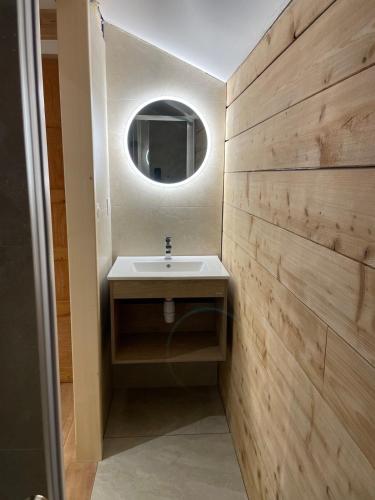 a bathroom with a sink and a round mirror at Chalet Les Balcons du Risoux in Bellefontaine