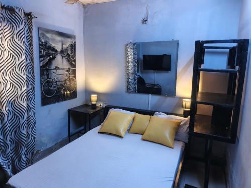 ein Schlafzimmer mit einem weißen Bett und gelben Kissen in der Unterkunft RÉSIDENCE PRIVÉE 1 Chambre avec Salon, Cuisine Équipée, Climatisation, Wifi et Cour Individuelle in Ouagadougou