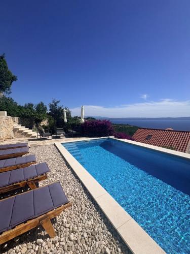 a swimming pool with chairs and the ocean in the background at sunset in Podgora