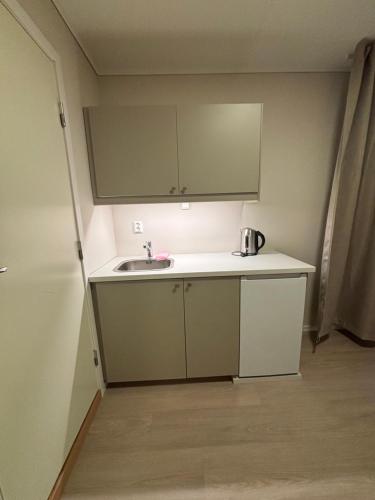 a small kitchen with a sink and a cabinet at Osterøy Minihotell in Lonevåg