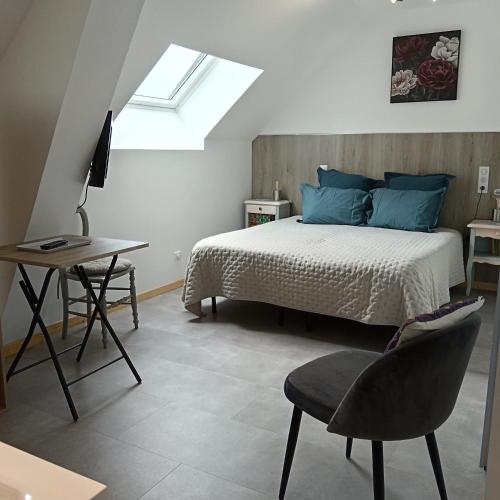 a bedroom with a bed and a table and a chair at L'ancienne forge 3 chambres d'hôtes à l'étage la forge , l'enclume et le marteau in Louvetot