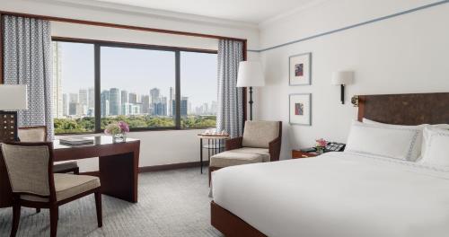 a hotel room with a bed and a desk and a window at The Peninsula Manila in Manila