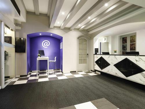 a room with a purple door and a table with a computer at ibis Styles Amsterdam Central Station in Amsterdam