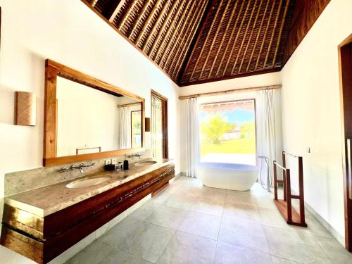 a bathroom with a tub and a sink and a mirror at Peninsula Bay Resort in Nusa Dua